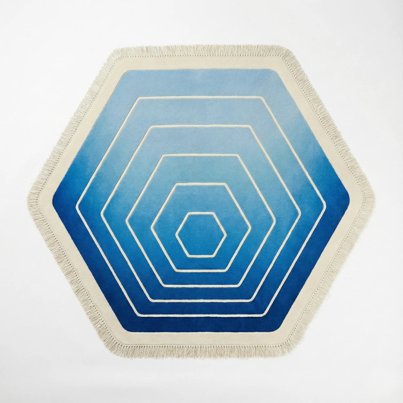 Hexagonal area rug with a concentric hexagon pattern in shades of blue and white, finished with a cream fringed border, shown on a plain white background.